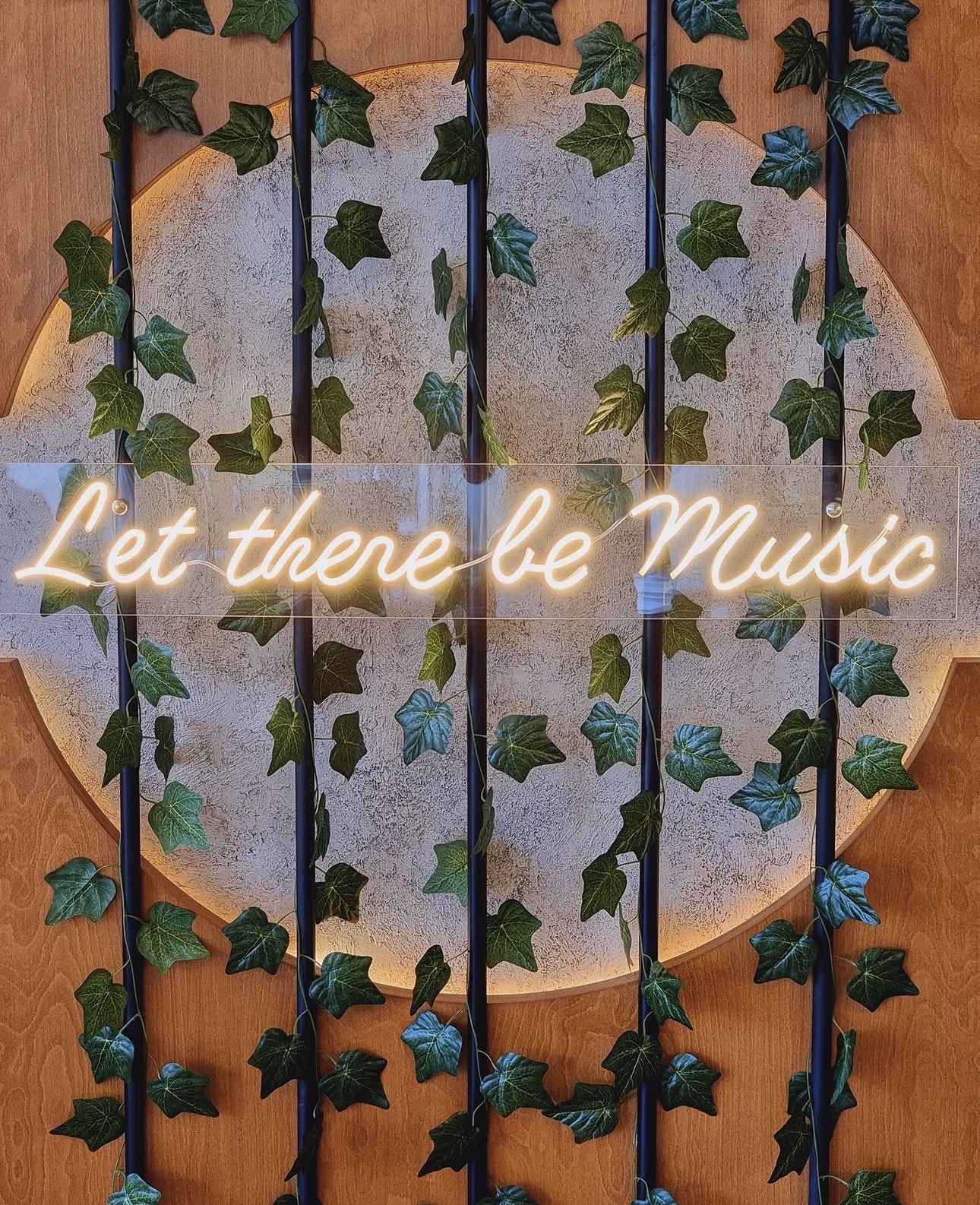 'Let there be Music' neon sign framed by ivy at Beit Setelkel
